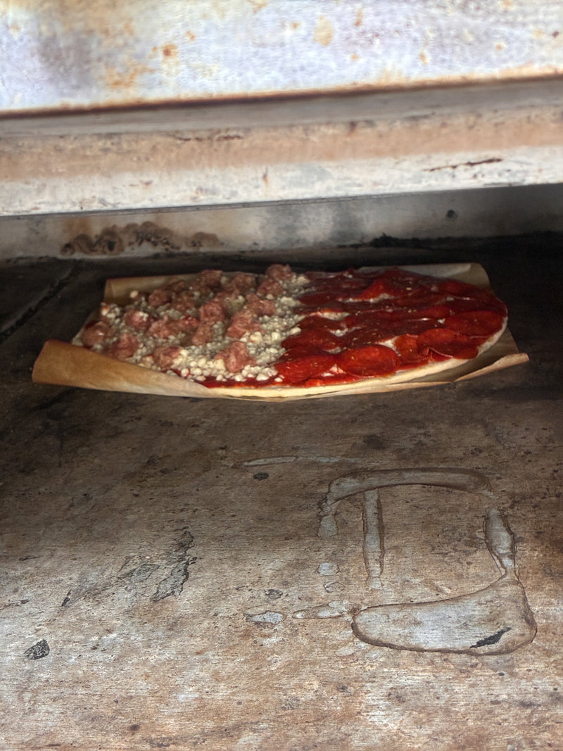 Sausage and pepperoni pizza going into the oven at Dudley's in Cannon Falls