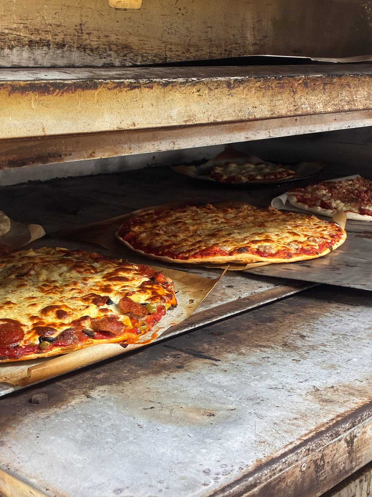 Pizzas in the oven at Dudley's Pizza in Cannon Falls, A Supreme, A Sausage, A Meat Eater's Delight, and a Gluten Free Sausage Pepperoni!